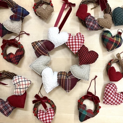 Guirlandas e corações decorativos em tecido com padrões variados e cores vermelha, branca, bege, verde e azul.