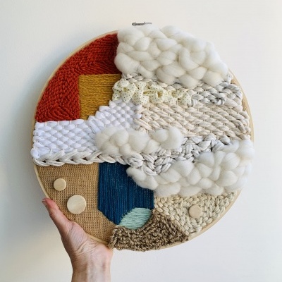 Obra de arte têxtil circular com lã branca felpuda e fios coloridos aplicados em base de madeira