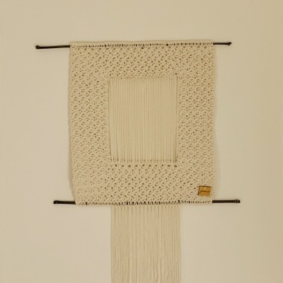 Tapeçaria de parede bege claro em macramé com franjas e varas pretas