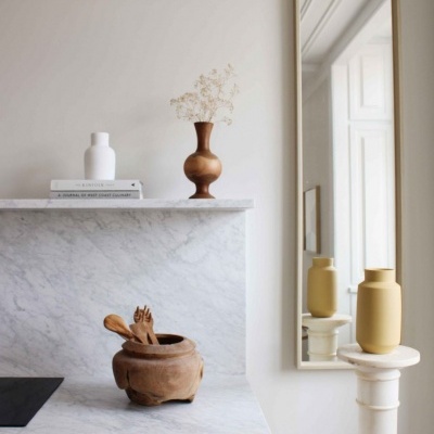 Cozinha com bancada de mármore e decoração com vasos e utensílios de madeira