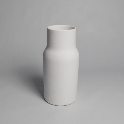 Vaso branco cilíndrico com textura mate sobre superfície cinzenta