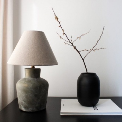 Mesa preta com candeeiro e vaso com galho seco