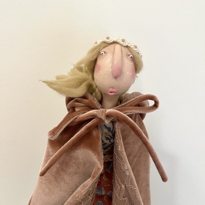 Boneca artesanal com capa de veludo rosa e coroa de flores pequenas