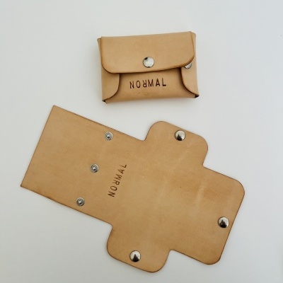 Carteira ou porta-cartões em pele castanha clara com texto NORMAL