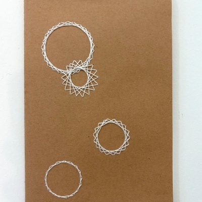 Caderno de capa castanha com bordados brancos e clipe preto no topo