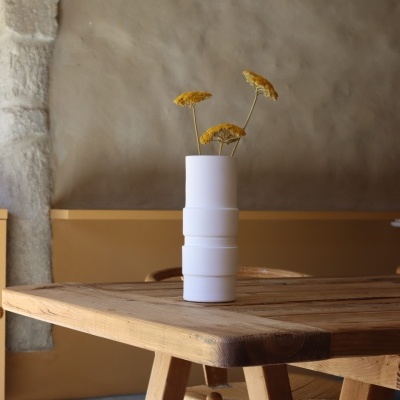 Vaso branco com flores amarelas sobre mesa de madeira em ambiente interior