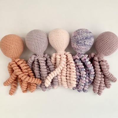 Cinco polvos de croché em tons pastel sobre fundo branco
