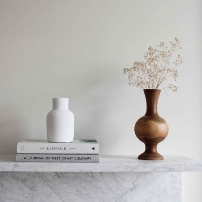 vaso branco e vaso de madeira com flores secas sobre lareira de mármore