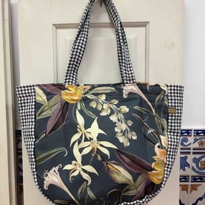 Mala de tecido floral e xadrez pendurada numa porta branca com azulejos decorativos