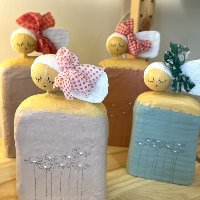 Bonecas decorativas em cerâmica com lenços coloridos expostas numa mesa de madeira