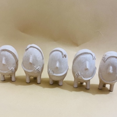 Cinco figuras decorativas brancas em linha sobre superfície bege