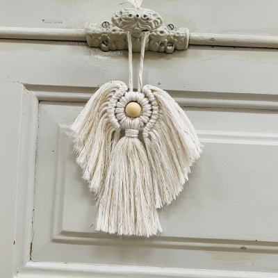 Enfeite de macramé em forma de anjo pendurado numa porta