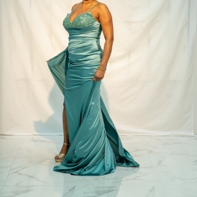 Vestido azul-turquesa acetinado com lantejoulas e racha numa mulher em fundo branco.