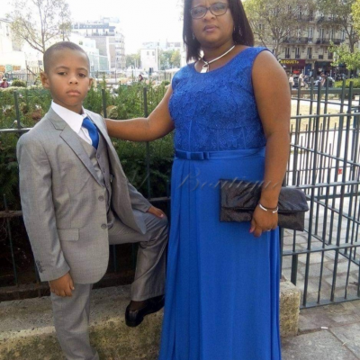 Homem jovem de fato cinzento e mulher com vestido azul comprido ao ar livre em cidade