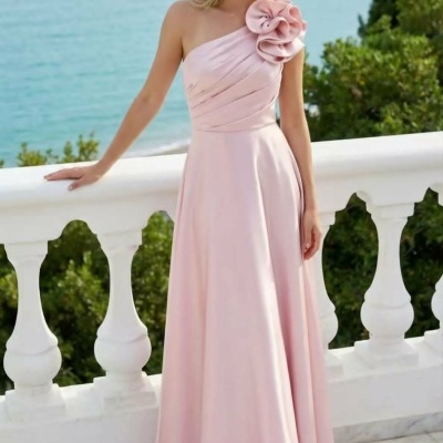 Vestido longo cor-de-rosa claro com flores no ombro, modelo ao ar livre com mar ao fundo