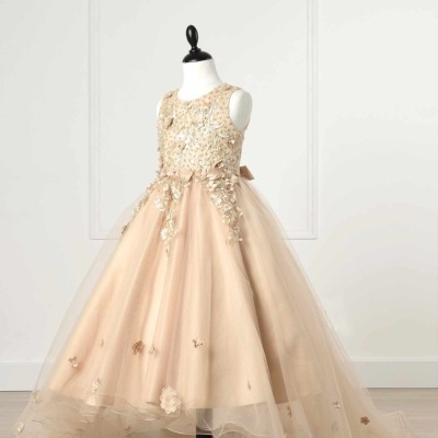 Vestido de criança bege com tule e flores em relevo exposto num manequim