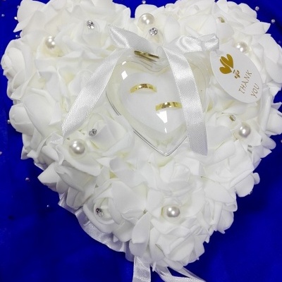 Almofada de flores brancas em forma de coração com anéis dourados e fita branca