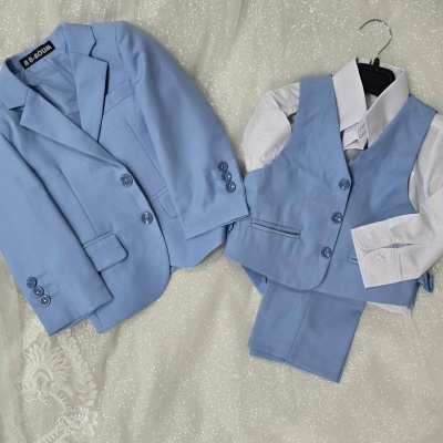 Conjunto roupa formal infantil azul claro com casaco, colete, camisa branca e calças sob fundo branco brilhante.