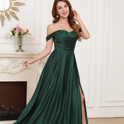 Vestido verde escuro com lantejoulas no decote e fenda lateral, mulher em ambiente elegante interior