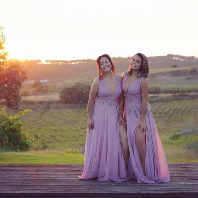 Duas mulheres com vestidos cor-de-rosa em campo ao pôr do sol