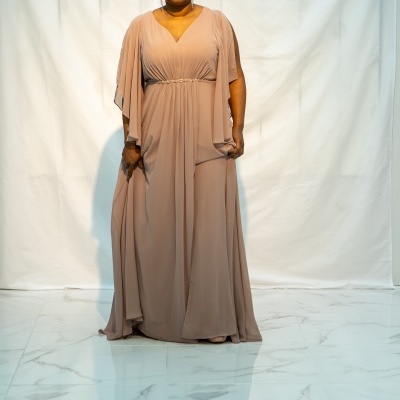 Vestido longo bege com mangas amplas e cinto fino no tronco.