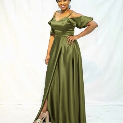 Mulher com vestido longo verde-oliva e sandálias bege em fundo branco