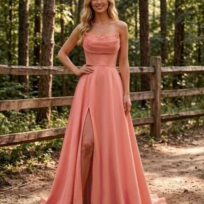 Vestido comprido cor coral com decote drapeado e renda, abertura frontal, ao ar livre junto a cerca de madeira e árvores.