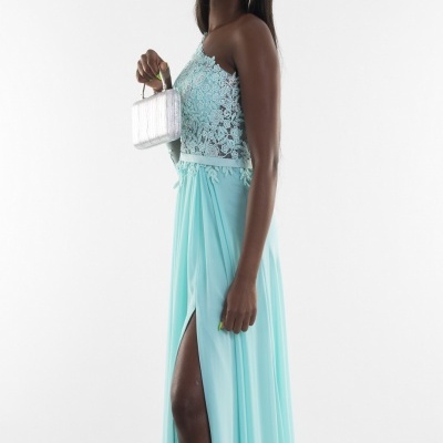 Vestido azul claro com renda floral e saia fluida com racha, mulher segura mala prateada