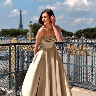 Mulher com vestido longo bege numa varanda com vista para a Torre Eiffel