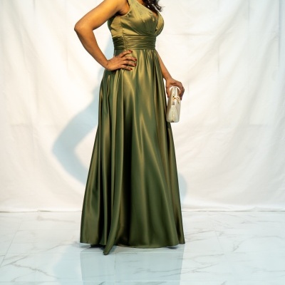 Mulher com vestido longo verde oliva acetinado e clutch bege