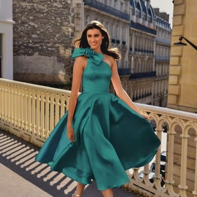 Vestido azul esverdeado com laço no ombro e sandálias douradas em rua urbana.