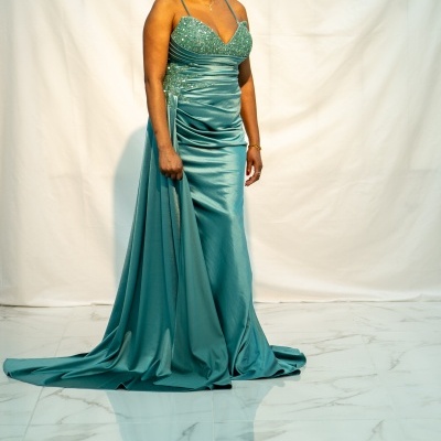 Mulher a usar vestido longo verde acetinado com alças finas e detalhes de lantejoulas.