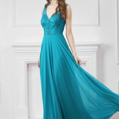 Vestido comprido azul turquesa com detalhes em renda e brilhantes, saia fluída, modelo feminino numa sala com chão de madeira e parede branca.