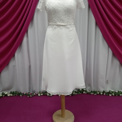 Vestido branco com renda e saia lisa em manequim com cortinas ao fundo