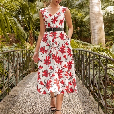 Vestido midi branco com flores vermelhas e cinto preto numa ponte com vegetação tropical