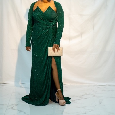 Mulher com vestido verde escuro brilhante e carteira bege