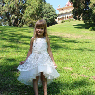 Criança de vestido branco em relvado com edifício ao fundo