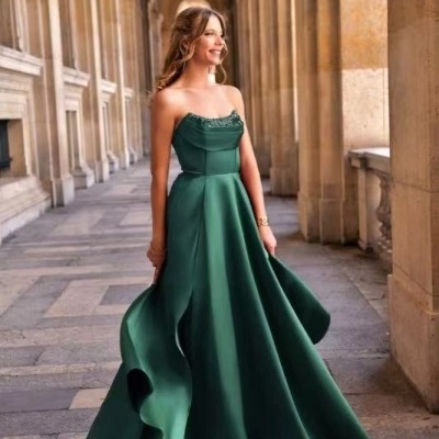 Mulher com vestido de festa verde escuro num corredor com colunas de pedra.