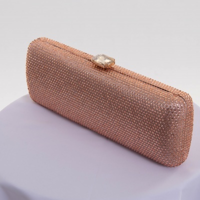 Mala de festa rose gold com pedras brilhantes e fecho cristal, sobre superfície lilás