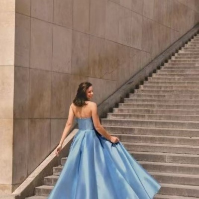 Mulher com vestido longo azul celeste em escadaria de pedra