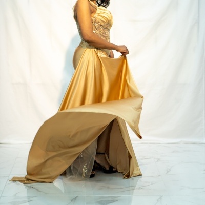 Mulher com vestido dourado brilhante em fundo branco e piso de mármore