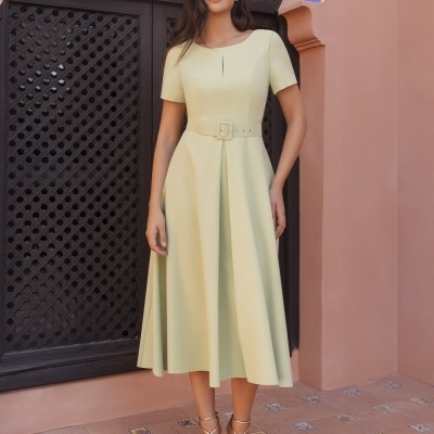 Vestido midi amarelo claro com cinto largo e sandálias douradas em ambiente exterior