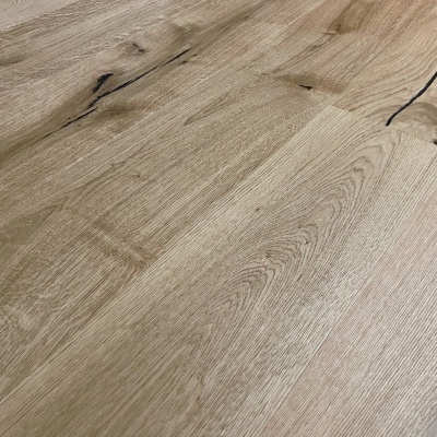 Painel de madeira clara com veios e nós visíveis sobre chão de madeira