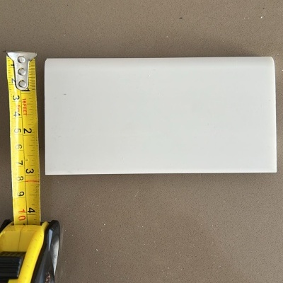 Item branco retangular com 10 cm medido por fita métrica amarela