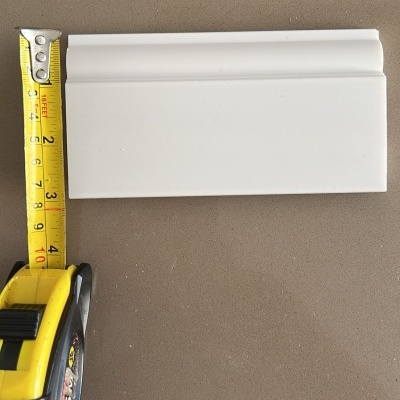 Fita métrica ao lado de moldura branca em superfície castanha