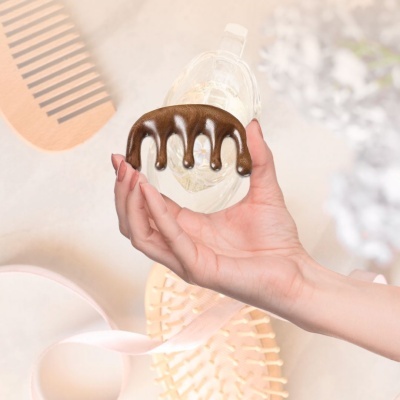 pente garra pequeno em madeira escura na mão sobre fundo com pentes e fita rosa