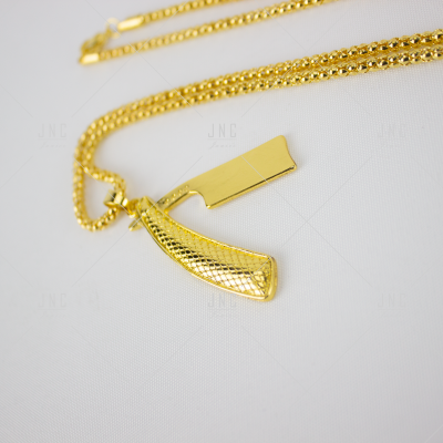 Colar dourado com pendente em forma de machado sobre fundo branco