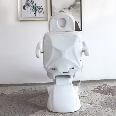 Cadeira médica branca com apoio para braços e encaixe para o rosto num ambiente interior com quadros na parede