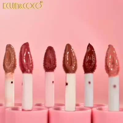 Seis aplicadores de batom líquido em diferentes tons sobre suporte rosa