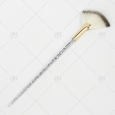 Pincel de maquilhagem com cabo transparente e cristais, ferragem dourada e cerdas brancas e pretas.